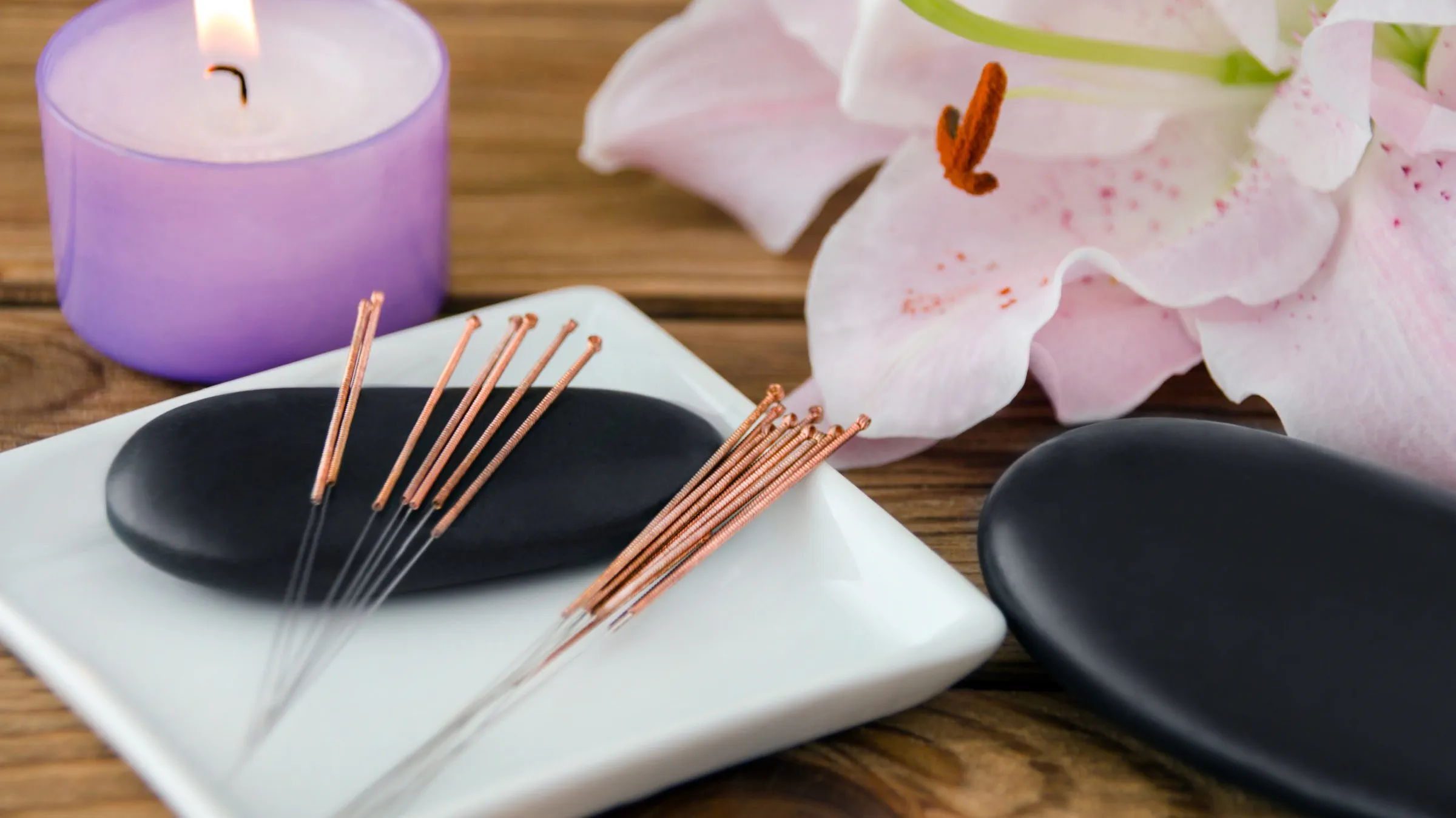 Acupuncture needles with a candle and flower